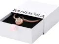Elegancka bransoletka Pandora z charmsami w kolorze różowego złota, ozdobiona cyrkoniami, w białym pudełku z różową wstążką.