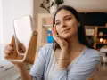 Kobieta z lustrem w dłoniach dotyka swojej twarzy, zastanawiając się nad bezpieczną pielęgnacją, np. czy retinol w ciąży jest dozwolony.