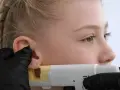 Profesjonalne przekłuwanie uszu u młodej dziewczyny. Widać pistolet do przekłuwania i rękawiczkę.