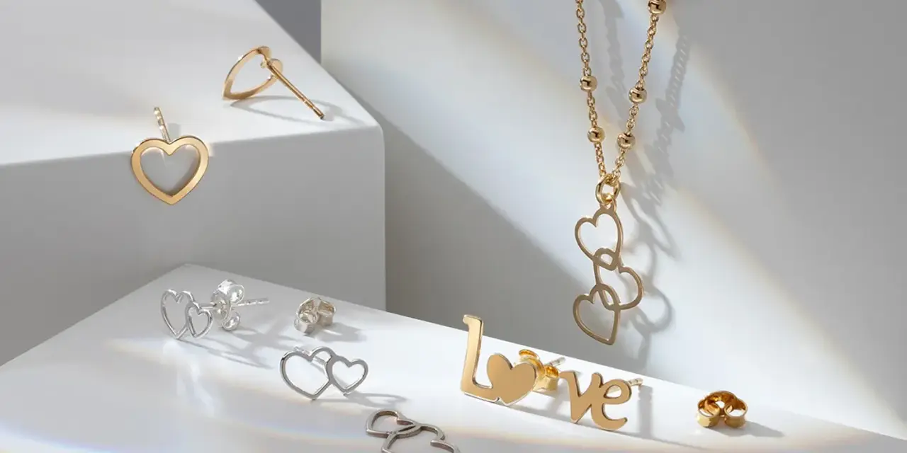 Złota biżuteria w kształcie serc i napisu "LOVE". Cechy złota: blask, trwałość i symbolika miłości.