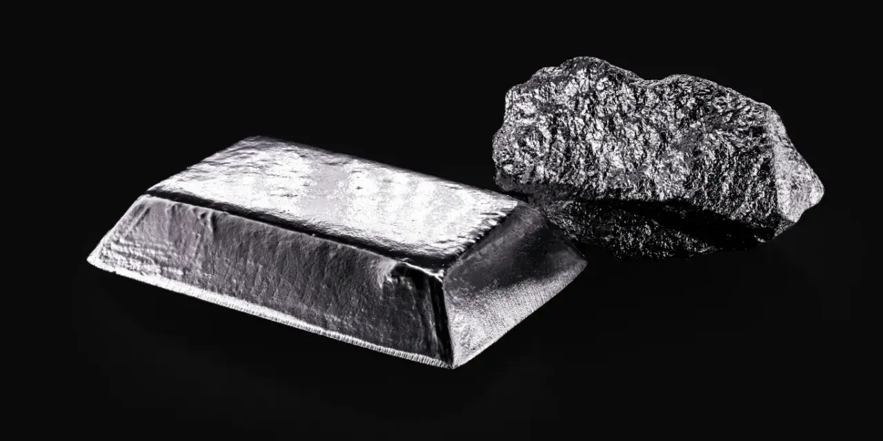 Sztabka i bryła platyny, najdroższego metalu szlachetnego, na czarnym tle.