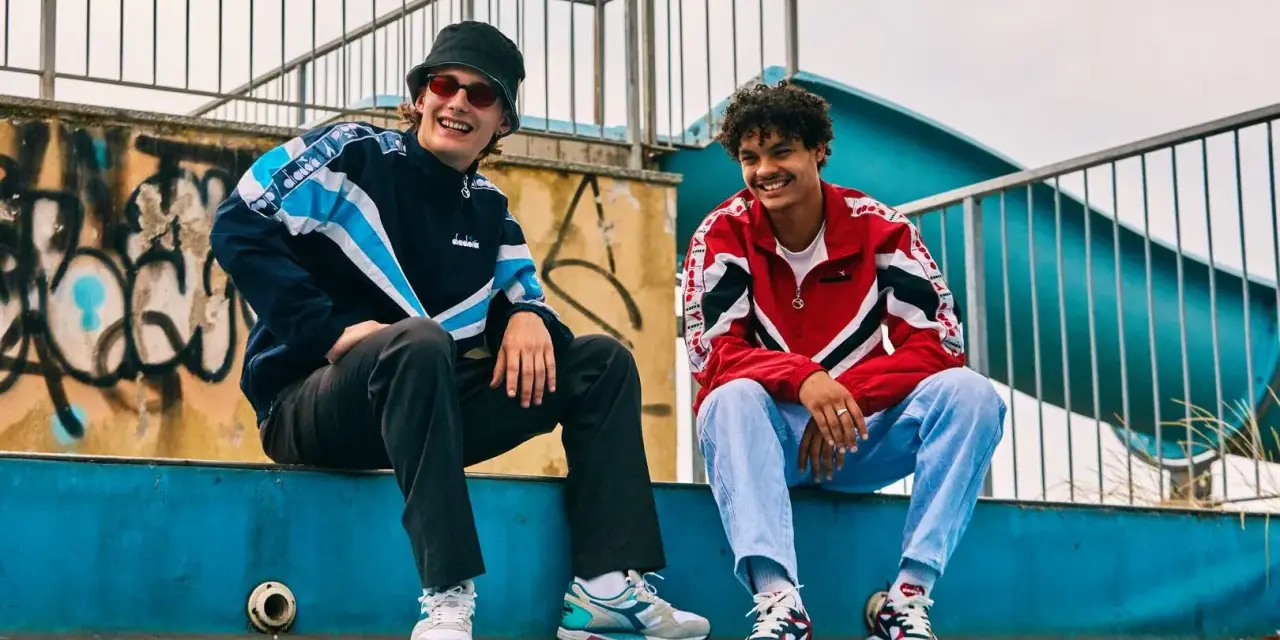 Dwóch uśmiechniętych chłopaków w kurtkach w stylu lat 80. Polska moda sportowa w najlepszym wydaniu.