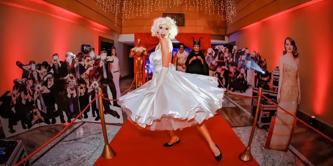 Impreza w stylu Hollywood: postać Marilyn Monroe na czerwonym dywanie, otoczona paparazzi i gwiazdami. Idealna inspiracja, jak się ubrać na galę!
