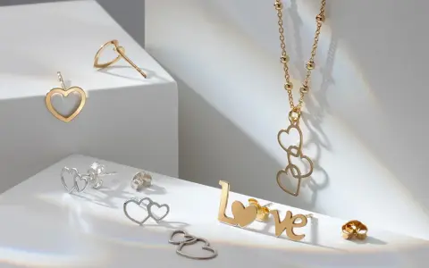 Złota biżuteria w kształcie serc i napisu "LOVE". Cechy złota: blask, trwałość i symbolika miłości.