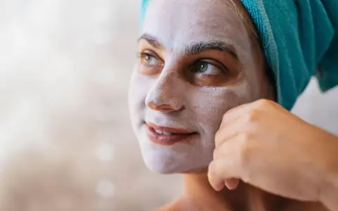Kobieta z maseczką na twarzy, która zawiera kaolin. To naturalna glinka, która oczyszcza i odżywia skórę.