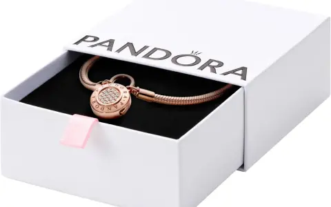 Elegancka bransoletka Pandora z charmsami w kolorze różowego złota, ozdobiona cyrkoniami, w białym pudełku z różową wstążką.