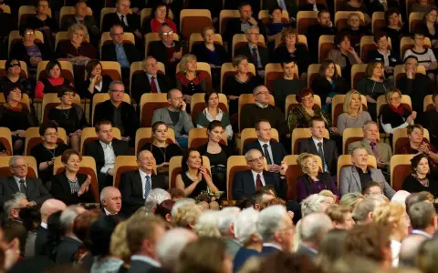 Elegancko ubrani ludzie siedzą w filharmonii, gotowi na koncert. Dowiedz się, jak ubrać się do filharmonii, by wyglądać stylowo.
