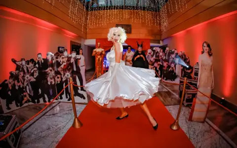 Impreza w stylu Hollywood: postać Marilyn Monroe na czerwonym dywanie, otoczona paparazzi i gwiazdami. Idealna inspiracja, jak się ubrać na galę!