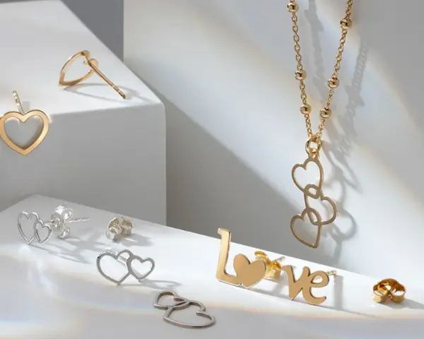 Złota biżuteria w kształcie serc i napisu "LOVE". Cechy złota: blask, trwałość i symbolika miłości.
