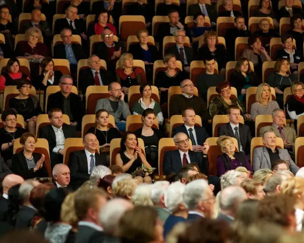 Elegancko ubrani ludzie siedzą w filharmonii, gotowi na koncert. Dowiedz się, jak ubrać się do filharmonii, by wyglądać stylowo.