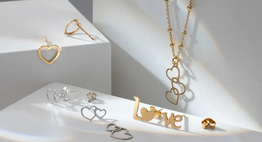 Złota biżuteria w kształcie serc i napisu "LOVE". Cechy złota: blask, trwałość i symbolika miłości.