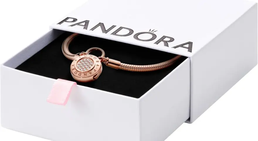 Elegancka bransoletka Pandora z charmsami w kolorze różowego złota, ozdobiona cyrkoniami, w białym pudełku z różową wstążką.