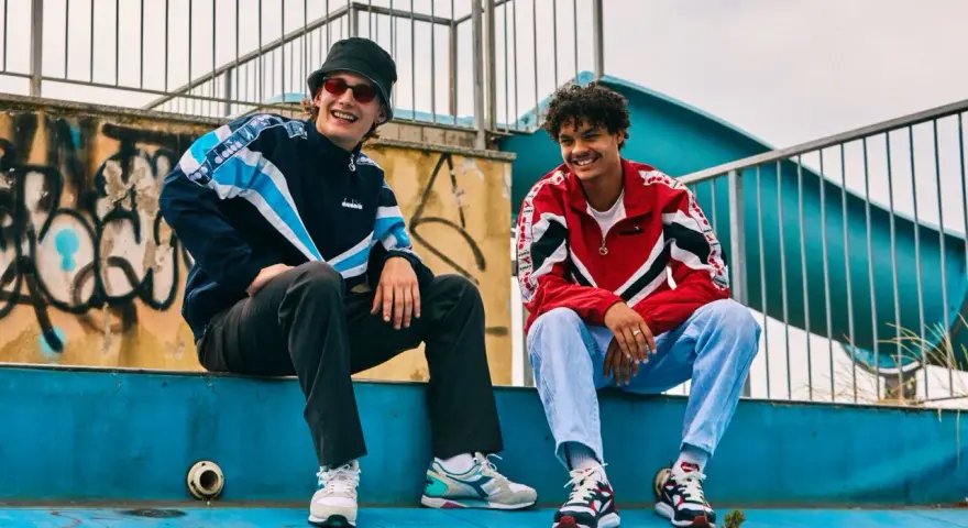 Dwóch uśmiechniętych chłopaków w kurtkach w stylu lat 80. Polska moda sportowa w najlepszym wydaniu.