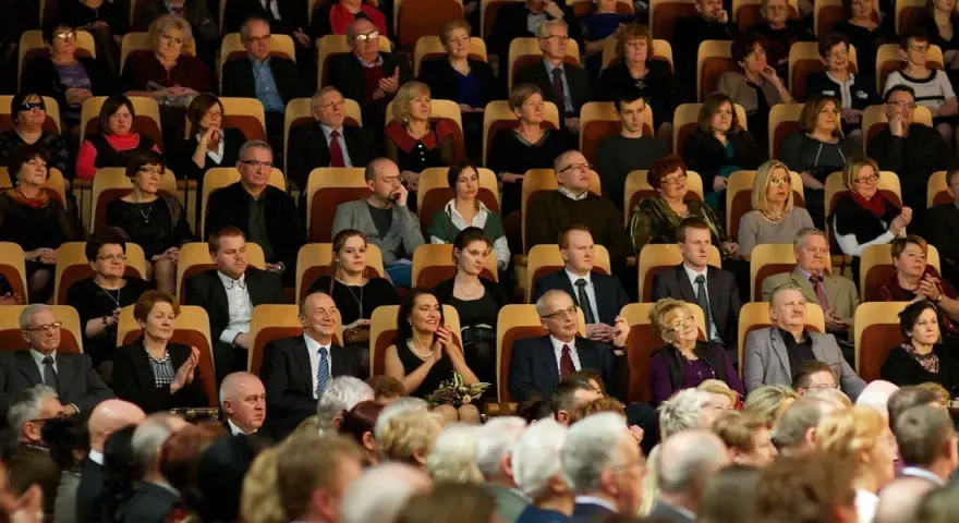 Elegancko ubrani ludzie siedzą w filharmonii, gotowi na koncert. Dowiedz się, jak ubrać się do filharmonii, by wyglądać stylowo.