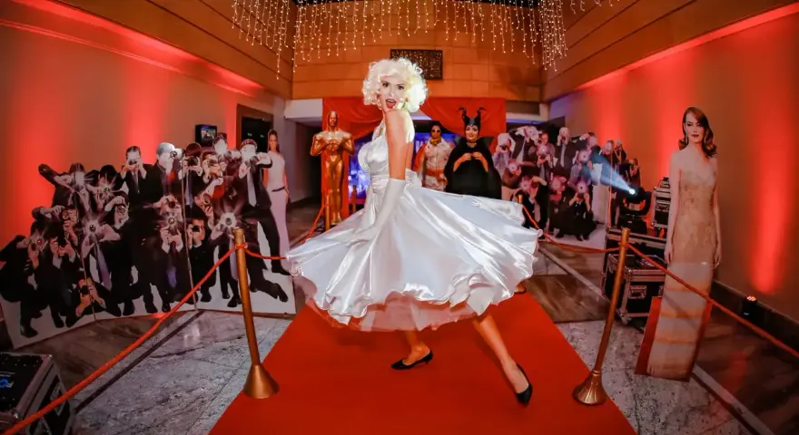Impreza w stylu Hollywood: postać Marilyn Monroe na czerwonym dywanie, otoczona paparazzi i gwiazdami. Idealna inspiracja, jak się ubrać na galę!