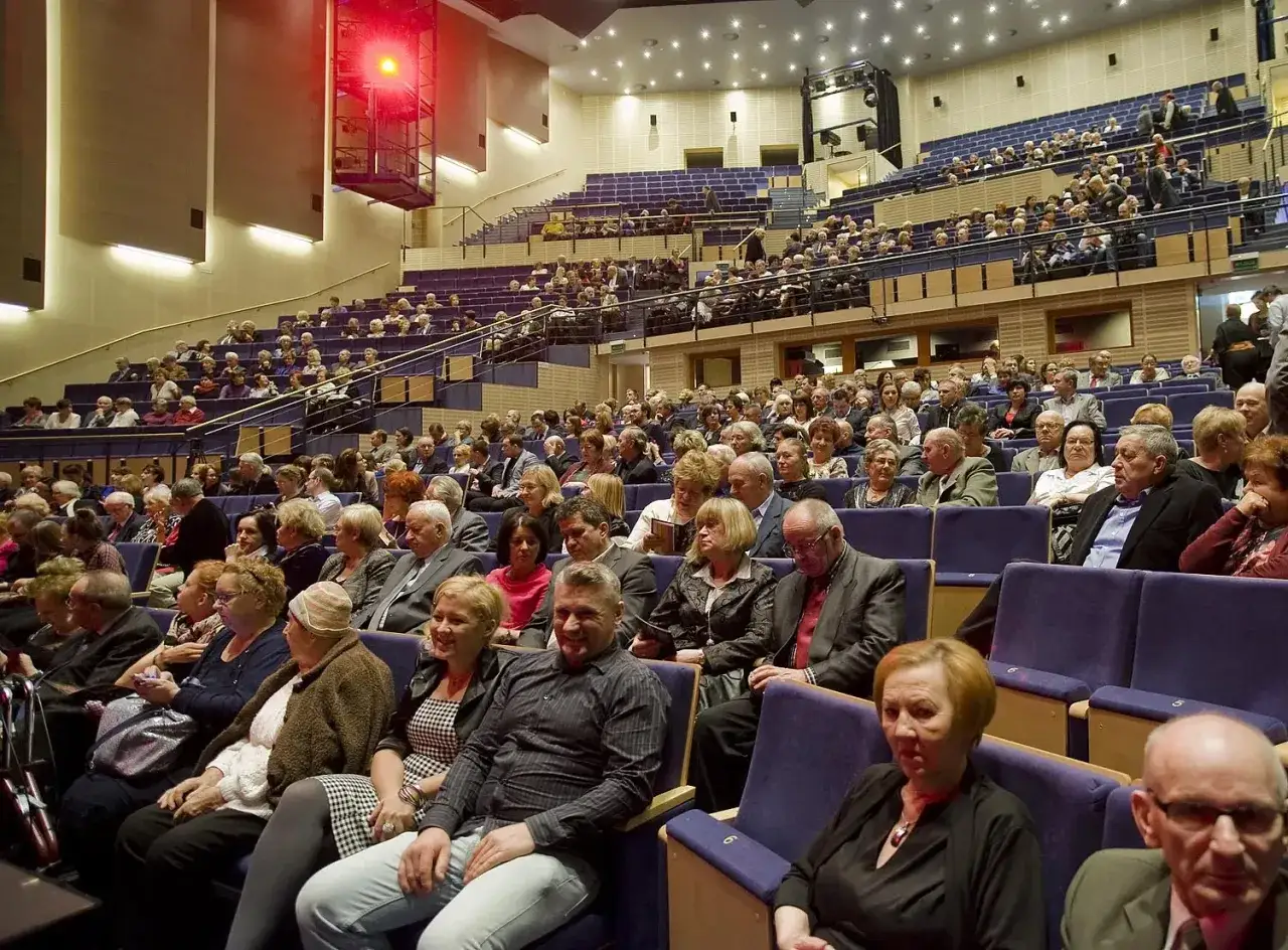 Widownia filharmonii w eleganckich strojach. Zastanawiasz się, jak ubrać się do filharmonii? Klasyczna elegancja zawsze się sprawdza.