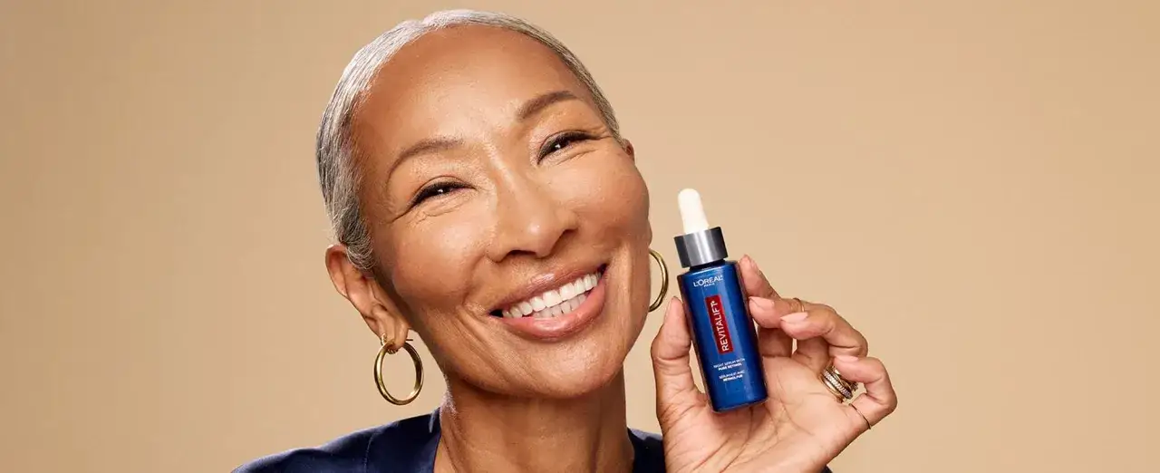 Uśmiechnięta kobieta trzyma serum z retinolem. Czy retinol to kwas? To pytanie nurtuje wiele osób dbających o cerę.