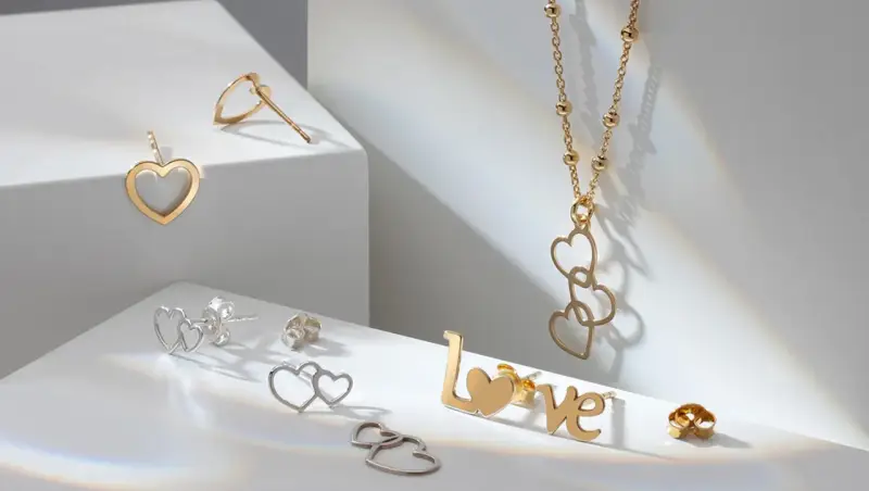 Złota biżuteria w kształcie serc i napisu "LOVE". Cechy złota: blask, trwałość i symbolika miłości.